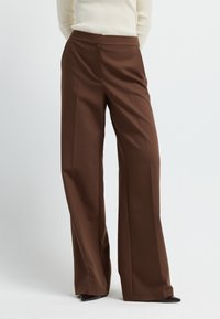 Bruine wijde broek gemaakt van zachte stof, met een op maat gemaakte tailleband en plooien, en een strakke, moderne silhouet.