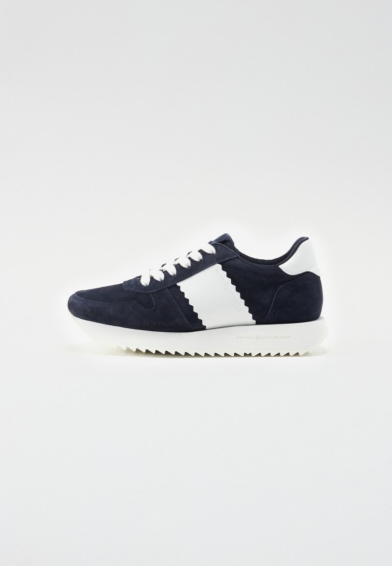 Tumesinine sametist sneaker, millel on valged aktsendid, tekstureeritud zikk-zakk mustril küljel ja hammastatud valge talla. Klassikaline nööridega disain.