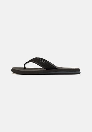 Chinelo preto com tira texturizada, sola de borracha plana e detalhe de logótipo discreto, projetado para uso casual e conforto.