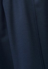 Tkanina w kolorze granatowym o gładkiej, teksturowanej powierzchni i subtelnym wzorze diagonalnym. Materiał wydaje się miękki i dobrze się układa.