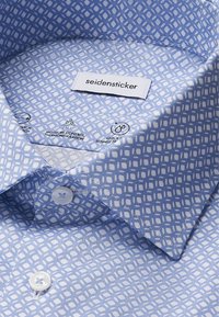 Lichtblauw gestreept shirt met een geometrisch wit ontwerp, knoopdetails en een aan genaaid etiket met de tekst "seidensticker."