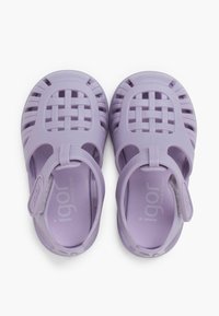 Purple plastic sandals with a woven design and back strap for secure fit. Smooth texture, open sides for ventilation, marked 'igor'.