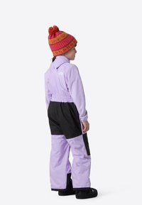 Μωβ και μαύρη χιονοστολή με ελαστική μέση, φλις πάνω μέρος και μεγάλα μπροστινά τσέπες. Ένα ροζ και πορτοκαλί πλεκτό καπέλο συμπληρώνει την εμφάνιση.