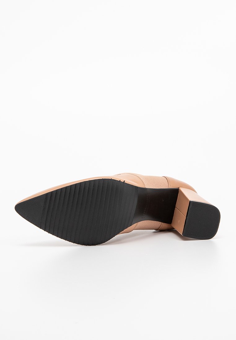 Nackter High Heel mit quadratischer Zehenpartie, strukturiertem Obermaterial und klobigem Blockabsatz. Die Sohle ist schwarz mit einem gestreiften Muster für besseren Halt.