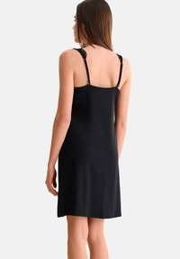 Robe noire sans manches avec de fines bretelles ajustables, présentant des accents en dentelle au niveau des épaules. Texture douce et lisse avec une coupe à mi-cuisse.