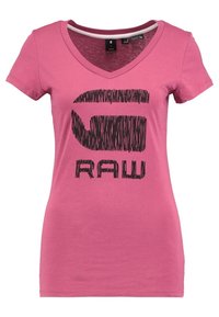 Lyserød bomulds V-hals t-shirt med stor sort grafisk tekst "G-RAW" i en struktureret skrifttype i midten. Korte ærmer, slim fit.