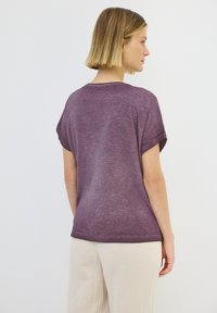 Lilla, T-shirt med korte ærmer og afslappet pasform, lavet af letvægtsstof. Har en rund halsudskæring og rullede ærmekanter.