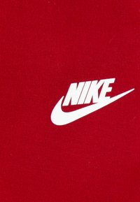 Material roșu cu un logo alb proeminent Nike, cu design swoosh, prezentat într-un font îndrăzneț și modern.
