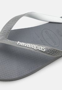 Chinelo de borracha cinza com solas texturizadas, tiras brancas e a marca "havaianas" em branco. Design leve, ideal para uso casual.