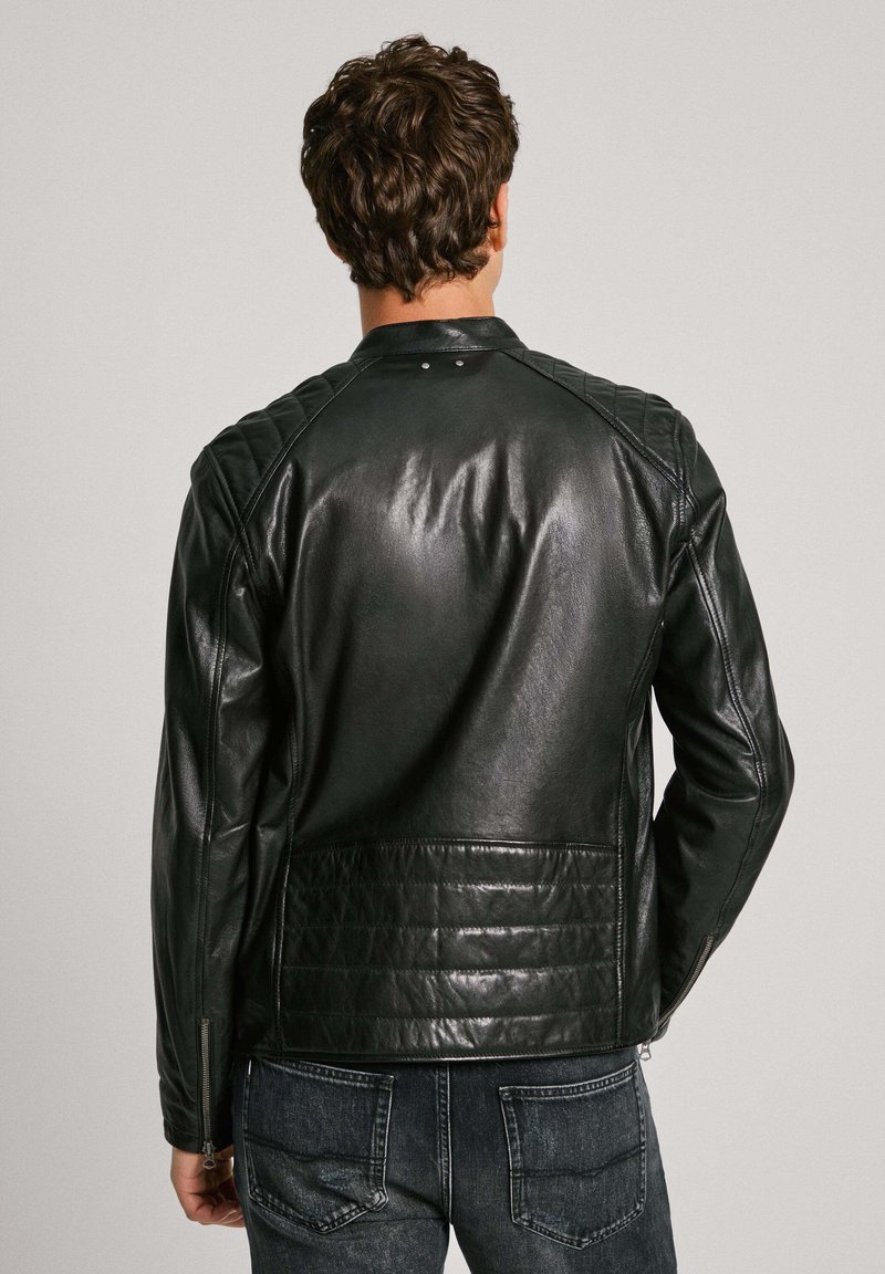 Chaqueta de cuero negra con una textura suave, detalle acolchado en los hombros y la espalda, cierre de cremallera y dos bolsillos traseros.
