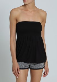 Zwarte strapless top met een gerimpelde buste, vloeiende stof en een relaxte pasvorm. Gecombineerd met grijze sportshorts met een geribde tailleband.