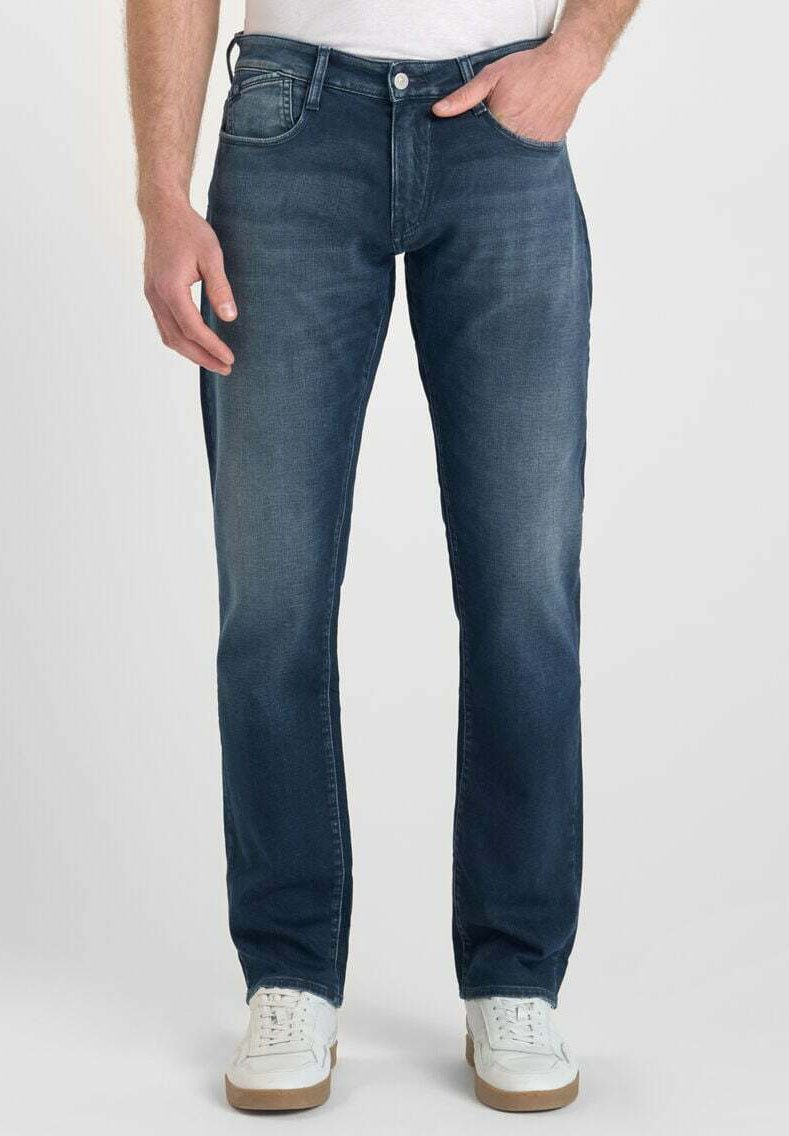 Donkerblauwe denim jeans met een rechte pijp, vijf zakken en subtiele vervaging. Gepaard met witte sneakers.