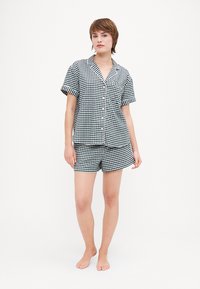 Rutete kortermet pysjamassett i svart og hvitt med skjorte med knapper og matchende shorts. Myk bomullsstoff, avslappet passform.
