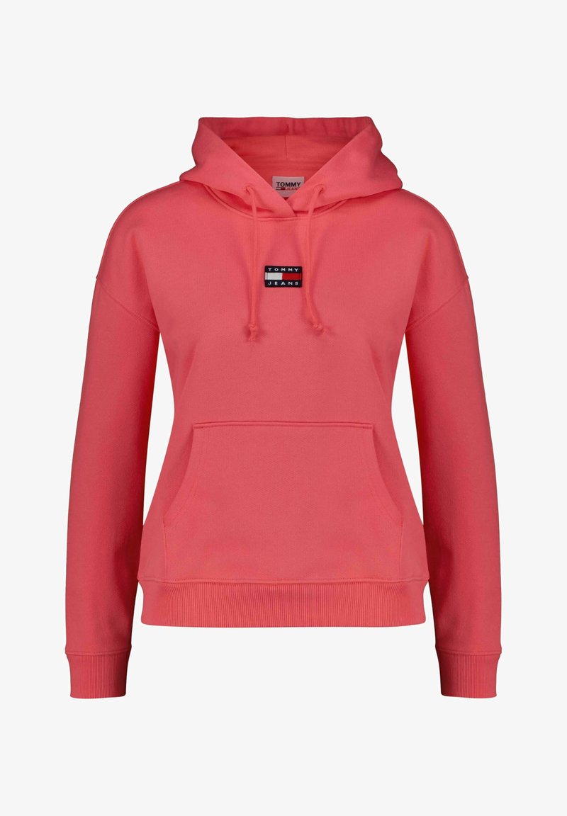 Coral pink hoodie with a large front pocket, drawstring hood, and a small black and white logo on the chest. Features ribbed cuffs and hem.