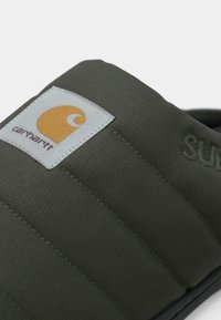 Grønne polstede slip-on fodtøj med tekstureret stof, der har et hvidt mærke med et orange logo og broderet "SUNDAY."