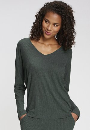 Green ribbed long-sleeve top with a V-neck, relaxed fit, and side pockets. Soft texture, featuring subtle vertical lines in the fabric.