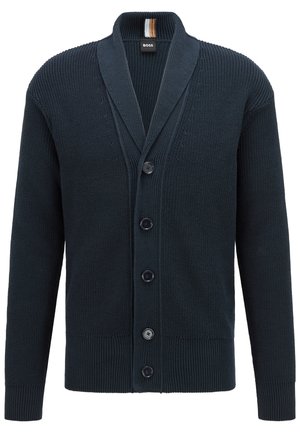 Granatowy sweter na drutach z kołnierzem szalowym, pięcioma guzikami z przodu, ściągaczami na mankietach i dole oraz małą czarną metką przy kołnierzu.