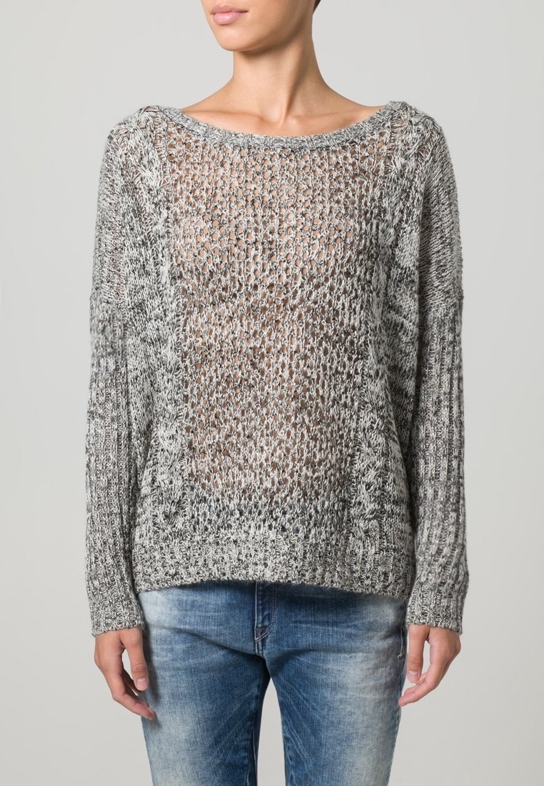 Maglione leggero e a maglia aperta in grigio e nero con scollatura ampia, maniche lunghe e polsini a coste. Indossato con jeans aderenti.
