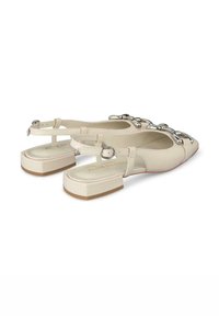 Beigefarbene Slingback-Schuhe mit spitzem Zehenbereich, dickem Absatz, verstellbaren Knöchelriemen und silbernen Schnallenakzenten an der Vorderseite.