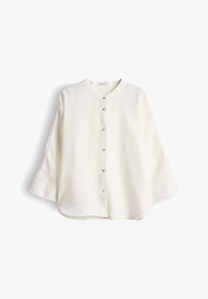 Witte blouse met lange mouwen, voorzien van een ronde kraag en zes knopen aan de voorkant, plat neergelegd tegen een witte achtergrond.