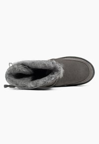 Botas de tobillo de ante gris con forro de pelo sintético y punta redonda. Presenta una suela texturizada y costuras decorativas a lo largo de los bordes.