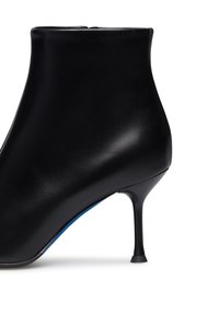 Stivale nero in pelle alla caviglia con texture liscia, forma affusolata e tacco sottile. Presenta una chiusura con zip sul retro e un tocco di blu all'interno.