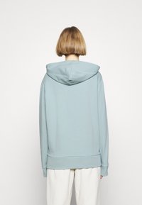 Sudadera con capucha de color azul claro, con una gran capucha, puños acanalados y dobladillo. Presenta una textura suave de mezcla de algodón con un corte relajado.