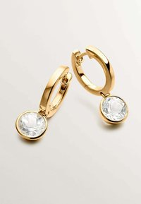 Pendientes de aro de oro con un acabado pulido, que presentan un colgante de cristal claro en forma de gota. Textura suave y brillante con un diseño moderno.