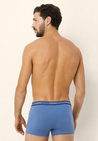 Blue cotton boxer shorts with a black waistband, featuring the brand "yamamay" printed. Smooth texture, fitted design, and mid-thigh length.