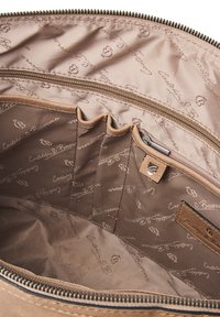 Bruine stoffen binnenkant van een tas met een ritsvak, compartimenten en een herhalend logo-patroon op een zijdezachte textuur.