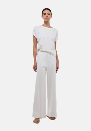 T-shirt en jersey de coton blanc à manches retroussées, associé à un pantalon blanc ample avec une taille élastique. Design simple et minimaliste.