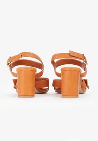 Brune hælede sandaler med blokhæle, ankelrem og flere remme over foden. Fremstillet af glat syntetisk materiale.