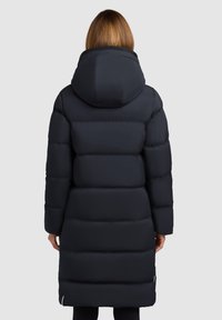 Tamsiai mėlyna pūkinė striukė su aukštu apykaklės ir kapišonu. Dizainas turi siūtas dalis izoliacijai ir tiesų kirpimą iki kelių.