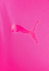 Jasně růžová sportovní tkanina s poloprůhledným logem skákající pumy, centrální design se strukturovaným povrchem.