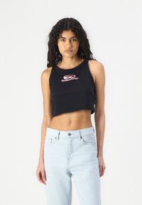 Must värviline crop tank top ümara kaelusega, millel on punane ja valge Quiksilveri logo. Kombineeritud helesiniste kõrge vöökohaga teksadega.