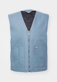 Gilet en toile bleu avec un décolleté en V, fermeture éclair sur le devant et deux grandes poches ; intérieur matelassé noir avec un patch logo sur le côté gauche.