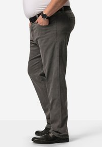 Pantalones de chándal grises con un ajuste relajado, piernas rectas, bolsillos laterales y una textura sutil, complementados con zapatos negros y un reloj.
