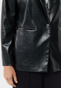 Czarna skórzana marynarka o gładkiej teksturze, z zapięciem na jeden guzik i dwiema przednimi kieszeniami. Dopasowany krój z czystymi liniami i minimalnymi detalami.