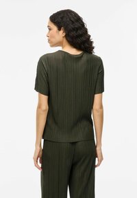 Top verde scuro a maniche corte con una texture a coste, dotato di scollatura tonda e vestibilità rilassata, abbinato a pantaloni coordinati.