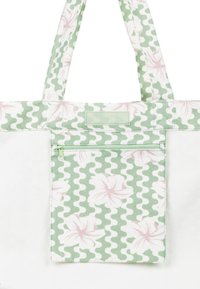 Green and white tote bag with a floral pattern and wavy design, featuring a front zip pocket and two sturdy straps.
