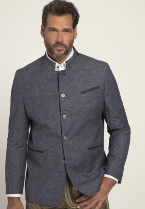 Chaqueta texturizada azul marino con cuello mandarín, botones plateados y dos bolsillos laterales. Cuello de camisa blanca visible debajo de la chaqueta.