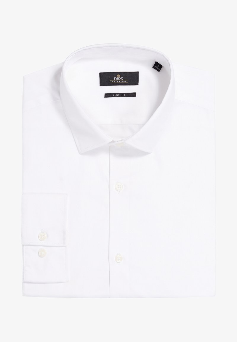 Chemise blanche ajustée en tissu de coton lisse, avec un col classique, une fermeture à boutons et des poignets à double bouton. Étiquette de la marque visible.