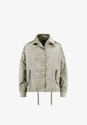 Jasnobeżowa, nylonowa kurtka z długim rękawem, kołnierzem, przednimi kieszeniami, elastycznym pasem i troczkami, pokazana na białym tle.