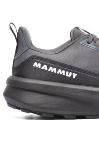 Svart idrottssko med en strukturerad överdel, dämpad mellansula och en framträdande vit "MAMMUT"-logotyp på sidan.