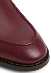 Bordeaux leren schoen met een gladde textuur, ronde vorm en contrasterende bruine stiksels langs de naad en de donkere zolenrand.