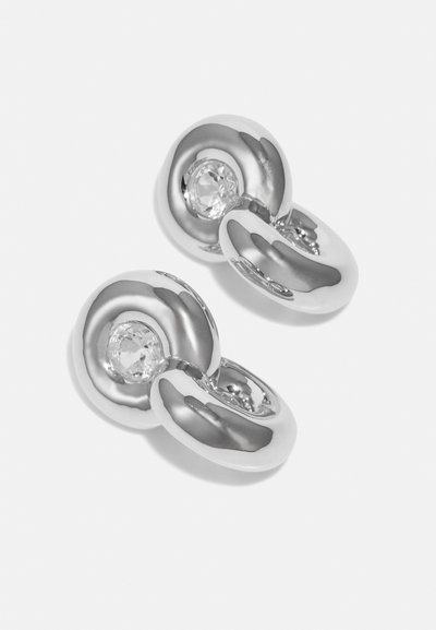 Silverörhängen med en slät, vriden design och en klar ädelsten som är inlagd i mitten av varje del.