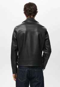 Veste de moto en cuir noir avec un col pointu, des poignets zippés et des détails de sangle sur les côtés. Texture lisse et coupe ajustée.