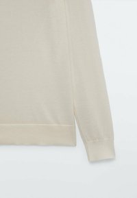 Beżowy sweter z długim rękawem, z prążkowanymi mankietami i pasem, pokazany na plain białym tle.