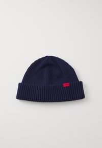 Gorro de punto azul marino con diseño de canalé, que presenta un puño doblado y una pequeña etiqueta de logo roja en el costado. Textura suave.