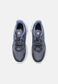 Trail running shoes in grey and blue, featuring a textured upper, integrated lacing system, and a durable rubber outsole.